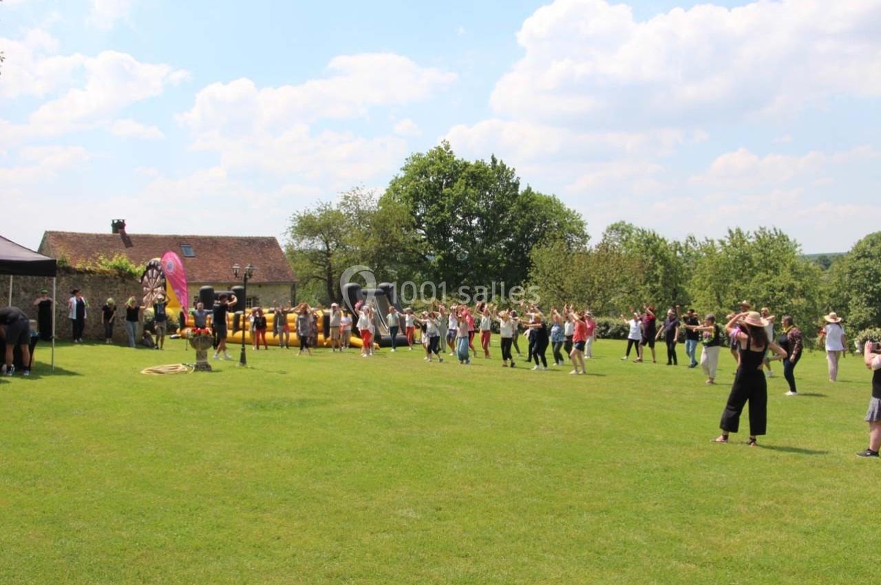 Groupe de personnes participant à une activité en plein air sur une pelouse par une journée ensoleillée.