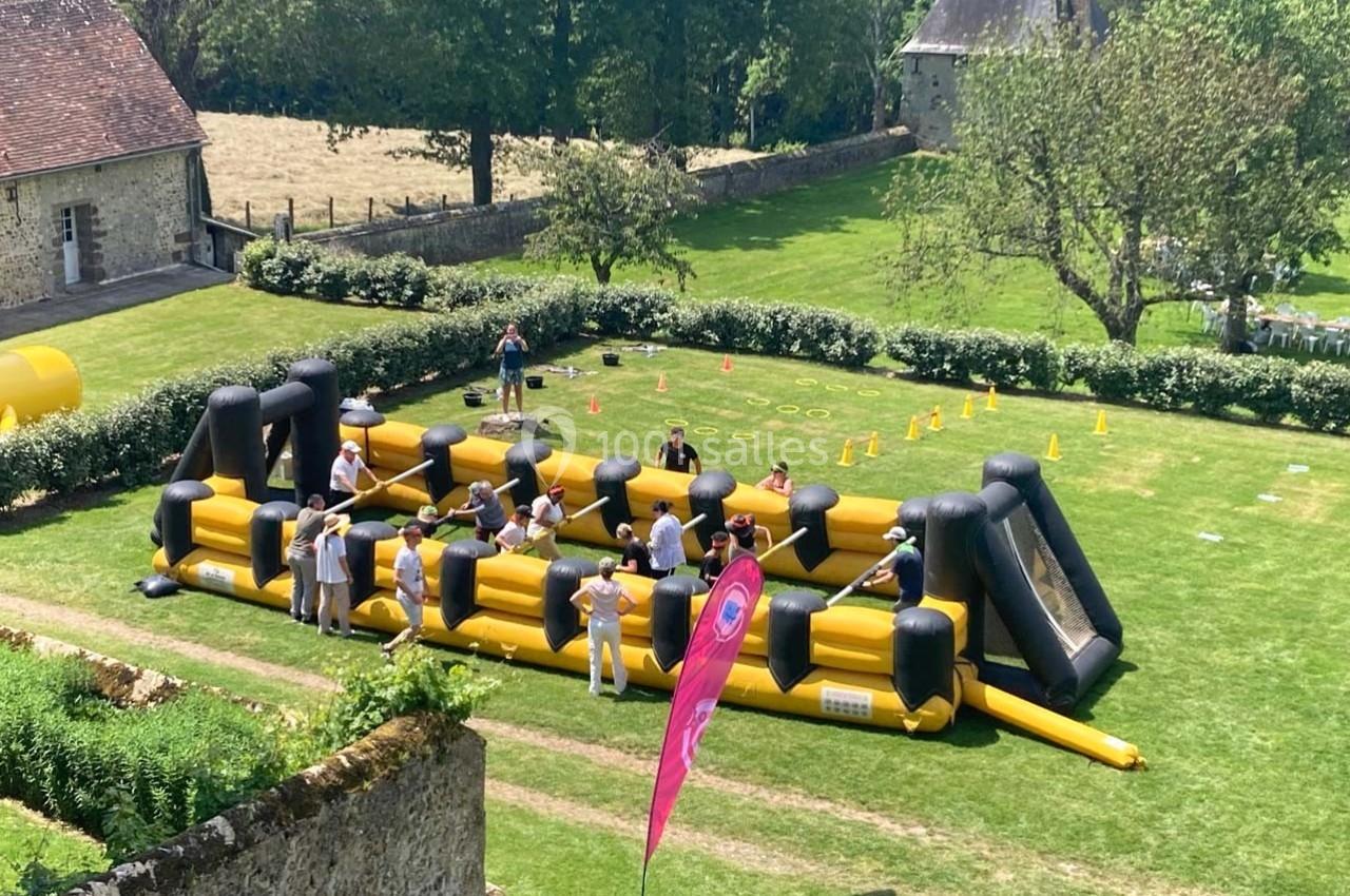 Structure gonflable jaune et noire utilisée pour une activité en plein air, avec des participants et des spectateurs.