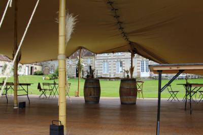 Salon rustique avec murs en pierre, canapés en cuir, table basse et porte ouverte donnant sur un jardin ensoleillé.