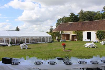 Salon rustique avec murs en pierre, canapés en cuir, table basse et porte ouverte donnant sur un jardin ensoleillé.