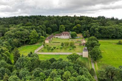 Salon rustique avec murs en pierre, canapés en cuir, table basse et porte ouverte donnant sur un jardin ensoleillé.