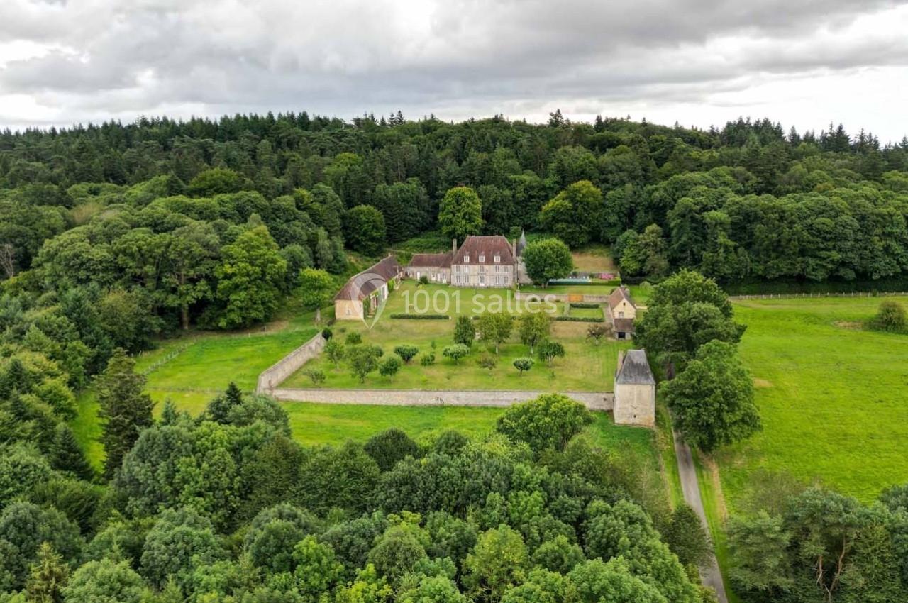 Vue aérienne d'un domaine historique entouré de forêts et de prairies, avec bâtiments et jardins clos.