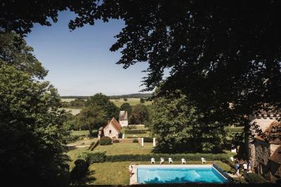 Salon rustique avec murs en pierre, canapés en cuir, table basse et porte ouverte donnant sur un jardin ensoleillé.