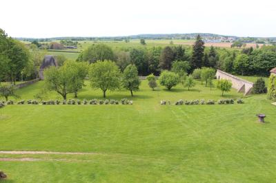 Salon rustique avec murs en pierre, canapés en cuir, table basse et porte ouverte donnant sur un jardin ensoleillé.