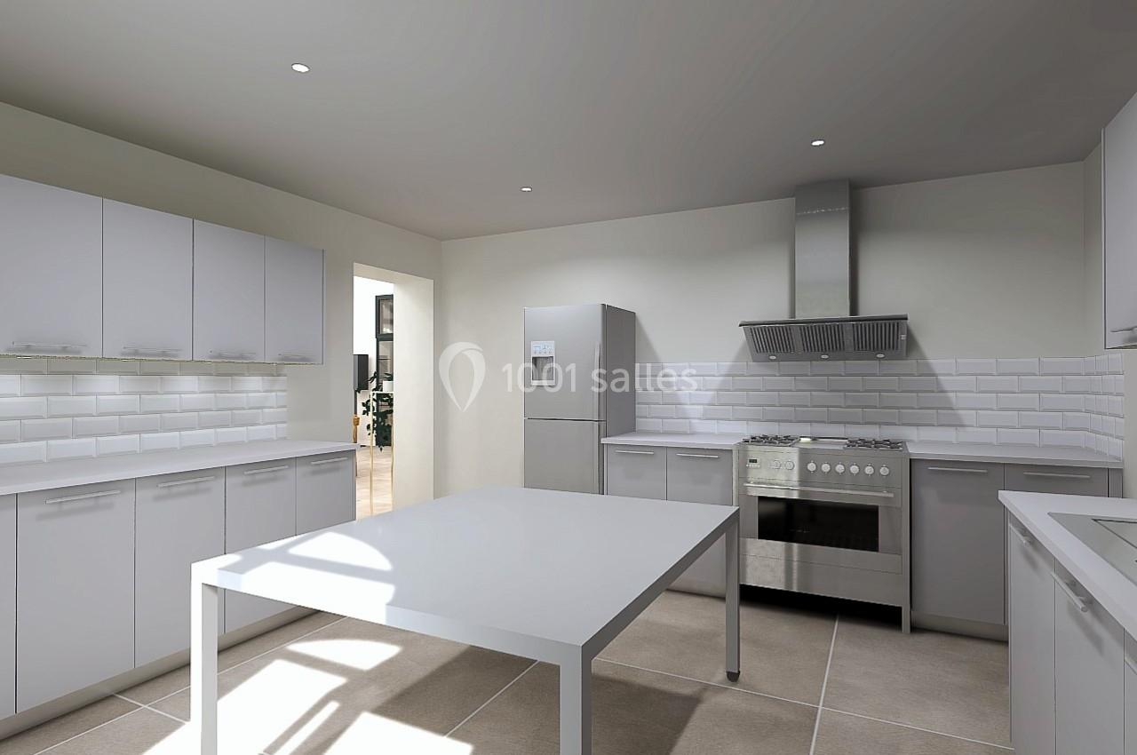 Cuisine moderne avec meubles blancs, table centrale, électroménagers en acier inoxydable et carrelage beige.