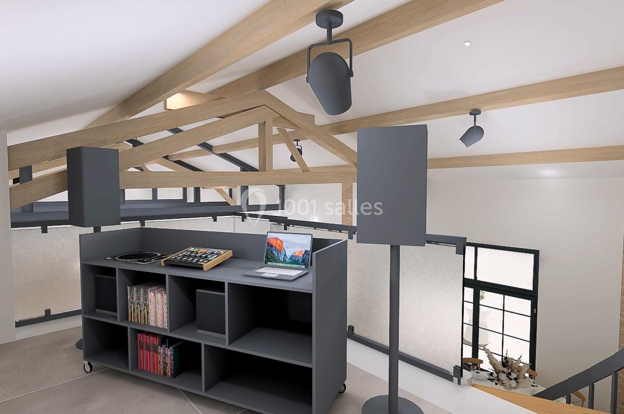 Meuble DJ avec platines, ordinateur portable et enceintes dans un intérieur moderne avec poutres apparentes.