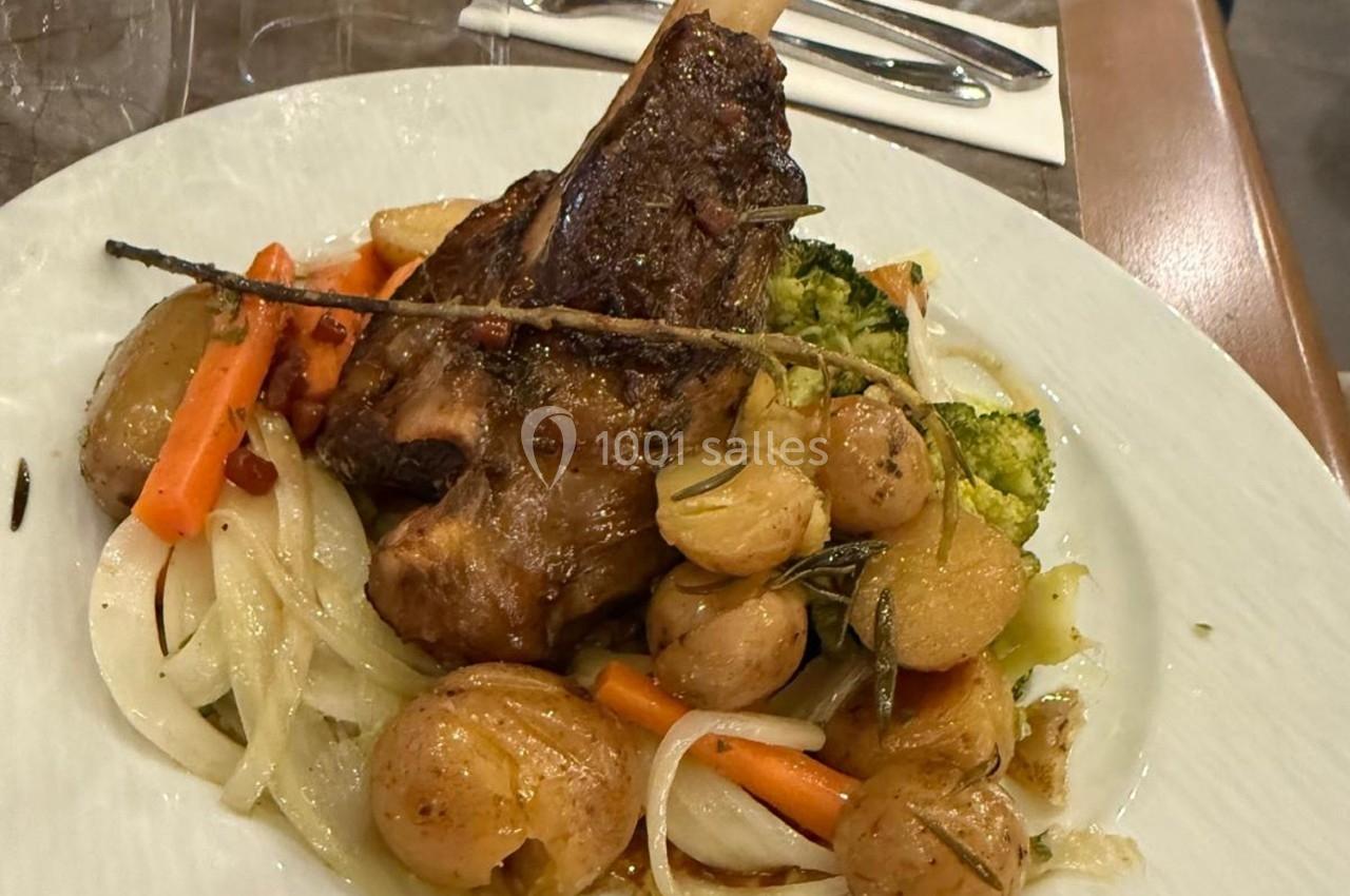 Assiette de jarret d'agneau braisé accompagné de légumes rôtis, pommes de terre et brins de romarin.