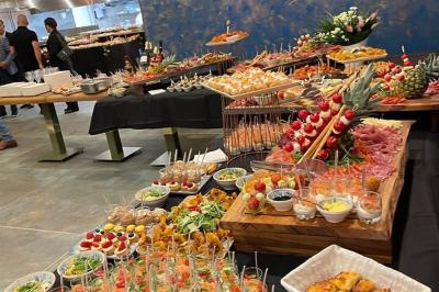 Buffet avec verrines, brochettes de fruits, amuse-bouches et coupes de vin sur une table en bois.