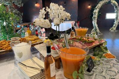 Buffet avec verrines, brochettes de fruits, amuse-bouches et coupes de vin sur une table en bois.