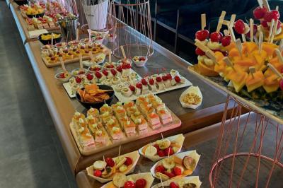 Buffet avec verrines, brochettes de fruits, amuse-bouches et coupes de vin sur une table en bois.