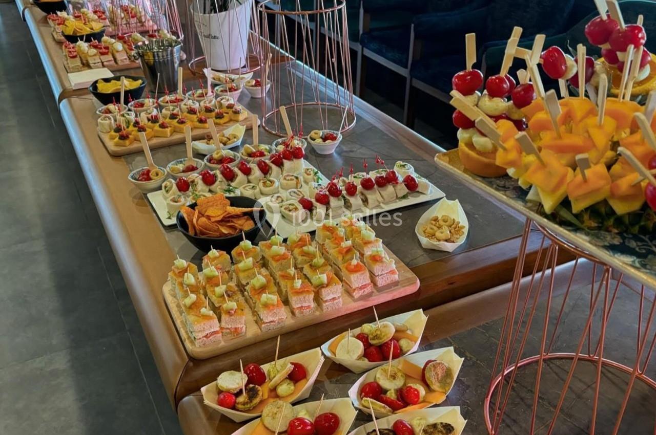 Buffet avec une variété de bouchées apéritives, incluant brochettes, canapés, verrines et amuse-bouches sur une table.