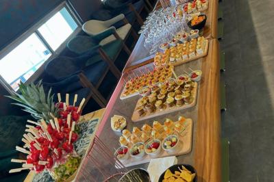 Buffet avec verrines, brochettes de fruits, amuse-bouches et coupes de vin sur une table en bois.