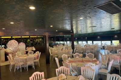 Salle de réception décorée avec des tables rondes dressées, chaises blanches et ambiance lumineuse chaleureuse.