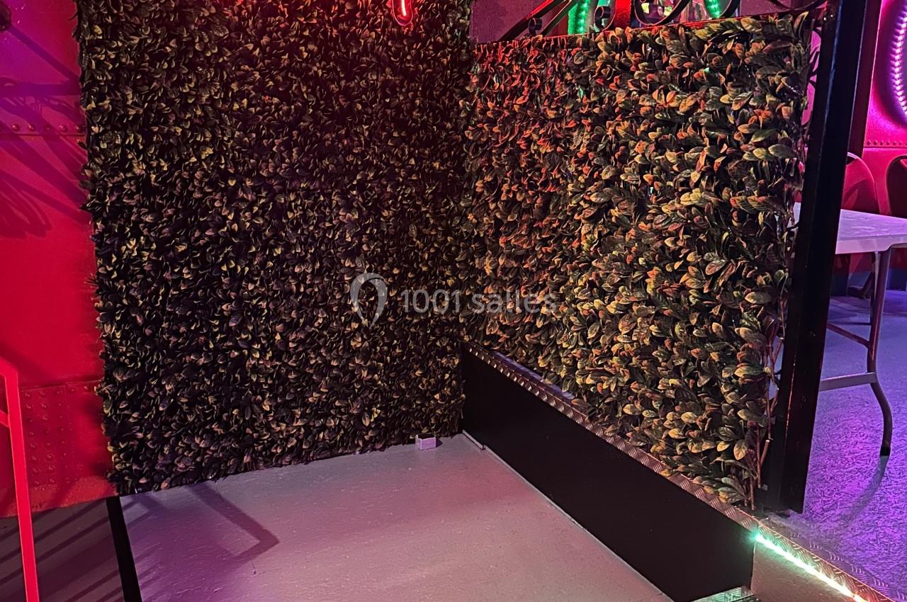 Mur végétal avec enseigne néon rouge ’Madison Cabaret’, éclairage coloré et rampe d'accès en premier plan.