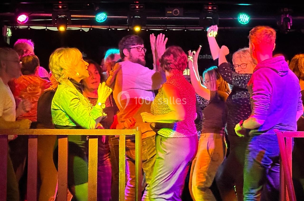 Groupe de personnes dansant sous des lumières colorées dans une ambiance festive.