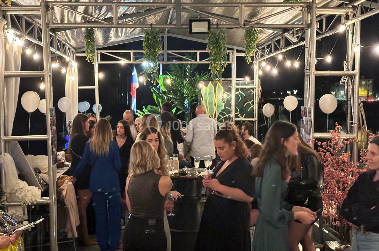 Groupe de personnes discutant et partageant un moment convivial sous une structure illuminée en soirée.