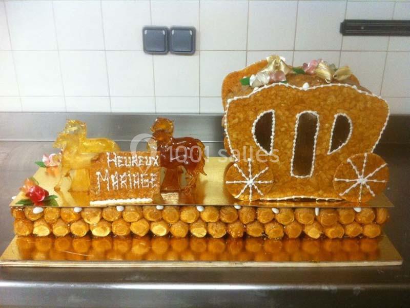 Pièce montée en forme de carrosse et chevaux en pâte à choux, décorée de fleurs en sucre et d'un message ’Heureux Mariage’.