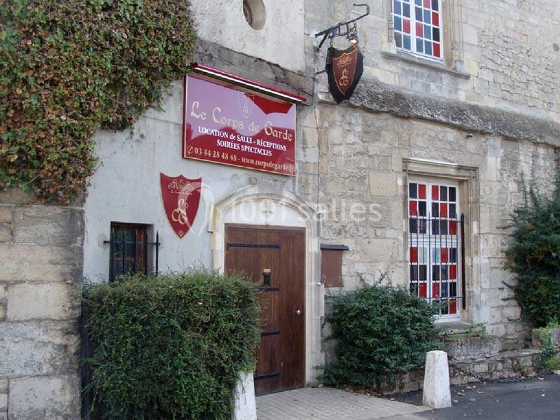 Façade en pierre d'un bâtiment ancien avec une enseigne indiquant une salle de réception et des armoiries décoratives.