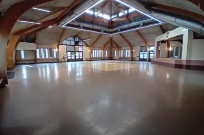 Espace intérieur avec murs en briques et pierres, sol carrelé blanc à motifs rouges, et comptoir circulaire en briques.