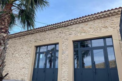 Terrasse en pierre avec piscine, chaises longues, parasols et bâtiments en pierre sous un ciel dégagé.