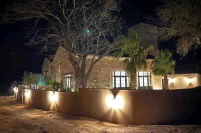 Terrasse en pierre avec piscine, chaises longues, parasols et bâtiments en pierre sous un ciel dégagé.