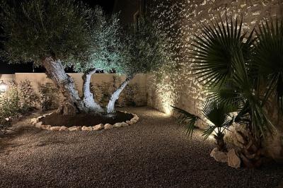 Terrasse en pierre avec piscine, chaises longues, parasols et bâtiments en pierre sous un ciel dégagé.