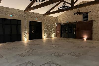 Terrasse en pierre avec piscine, chaises longues, parasols et bâtiments en pierre sous un ciel dégagé.