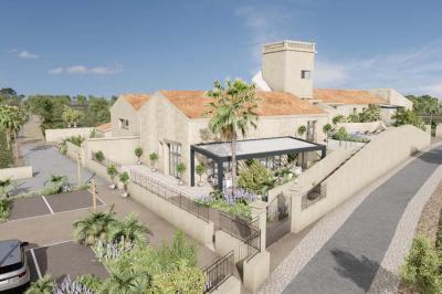 Terrasse en pierre avec piscine, chaises longues, parasols et bâtiments en pierre sous un ciel dégagé.