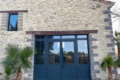 Entrée avec porte vitrée, mur végétal à droite, sol en béton et éclairage au sol.