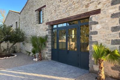 Entrée avec porte vitrée, mur végétal à droite, sol en béton et éclairage au sol.