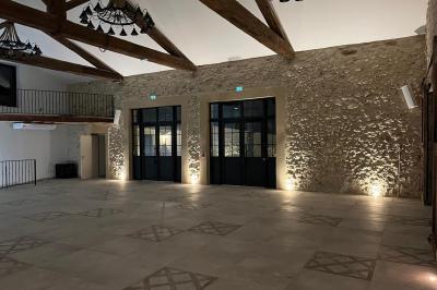 Entrée avec porte vitrée, mur végétal à droite, sol en béton et éclairage au sol.