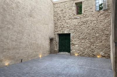 Entrée avec porte vitrée, mur végétal à droite, sol en béton et éclairage au sol.