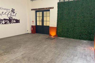 Entrée avec porte vitrée, mur végétal à droite, sol en béton et éclairage au sol.