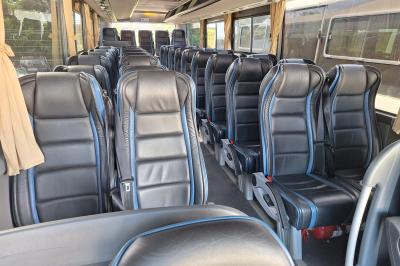 Intérieur d'un véhicule spacieux avec sièges en cuir noir, toit ouvrant et fenêtres équipées de rideaux.