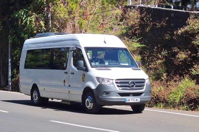 Intérieur d'un véhicule spacieux avec sièges en cuir noir, toit ouvrant et fenêtres équipées de rideaux.
