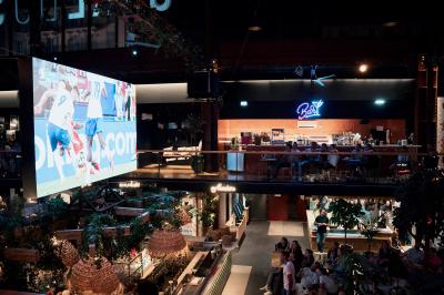 À gauche, des boules de pétanque sur un terrain sablonneux ; à droite, une façade de gare ensoleillée avec une horloge.