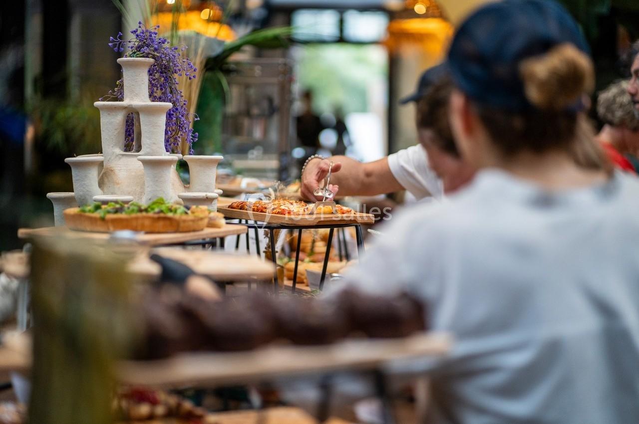 Personnes se servant à un buffet garni de plats variés, avec des fleurs décoratives en arrière-plan.