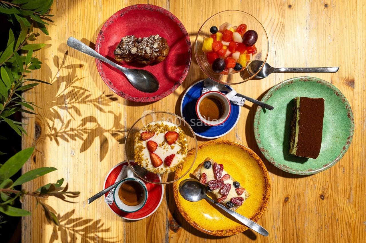 Desserts variés avec fruits, tiramisu et gâteau au chocolat, accompagnés de tasses de café sur une table en bois.