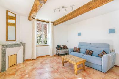 Petite voiture ancienne bleue avec toit ouvert, stationnée sur une pelouse près d'arbres et d'un bâtiment en arrière-plan.