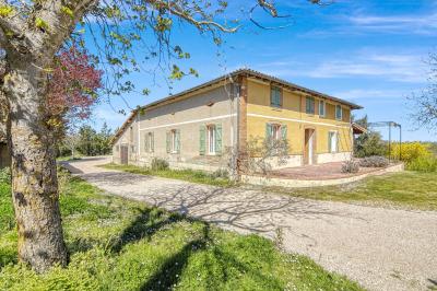 Petite voiture ancienne bleue avec toit ouvert, stationnée sur une pelouse près d'arbres et d'un bâtiment en arrière-plan.
