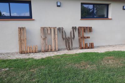 Petite voiture ancienne bleue avec toit ouvert, stationnée sur une pelouse près d'arbres et d'un bâtiment en arrière-plan.