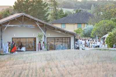 Petite voiture ancienne bleue avec toit ouvert, stationnée sur une pelouse près d'arbres et d'un bâtiment en arrière-plan.