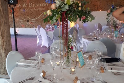 Petite voiture ancienne bleue avec toit ouvert, stationnée sur une pelouse près d'arbres et d'un bâtiment en arrière-plan.