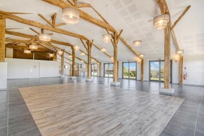 Un groupe de personnes participe à une réunion dans une salle avec des murs en pierre et une charpente apparente.