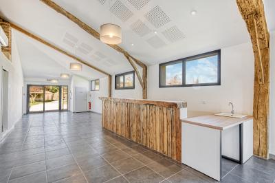 Un groupe de personnes participe à une réunion dans une salle avec des murs en pierre et une charpente apparente.