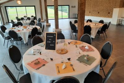 Un groupe de personnes participe à une réunion dans une salle avec des murs en pierre et une charpente apparente.