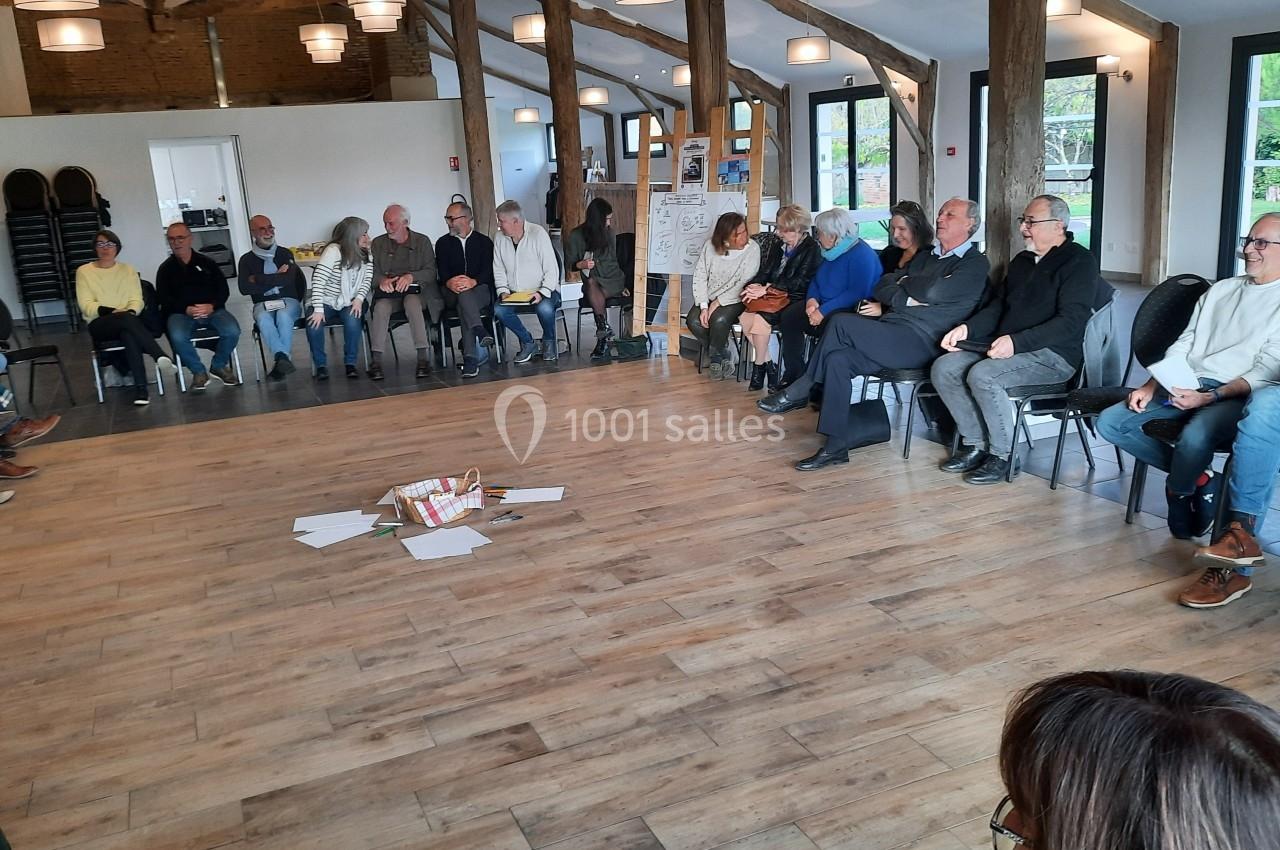 Un groupe de personnes assises en cercle dans une salle lumineuse avec des documents posés au centre.