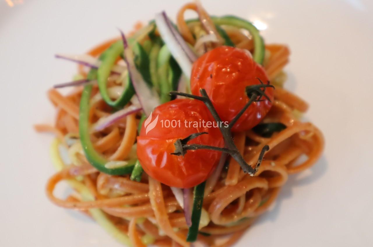 Assiette de linguines aux légumes et tomates cerises rôties, présentée sur un fond blanc.