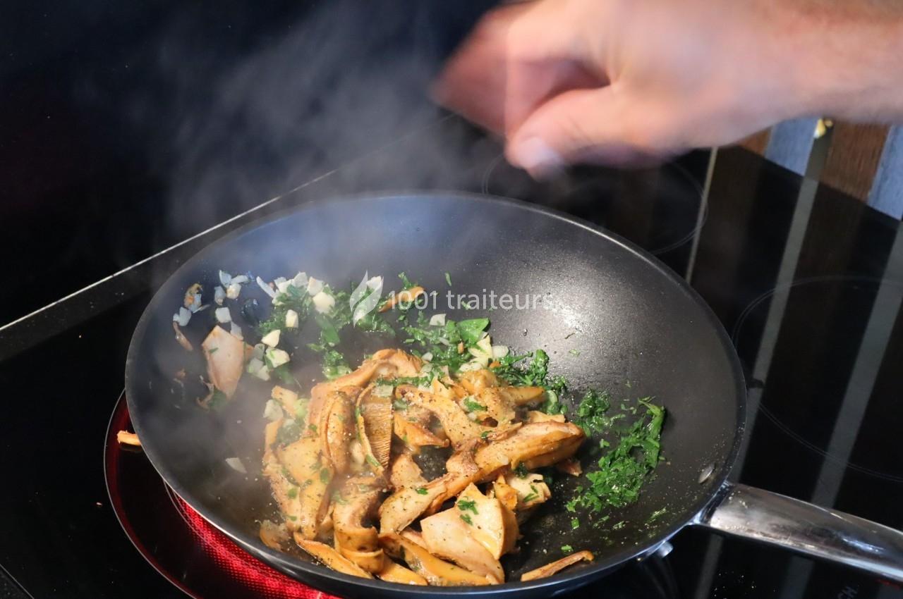 Champignons sautés avec des herbes fraîches et de l'ail dans une poêle, avec une main remuant les ingrédients.