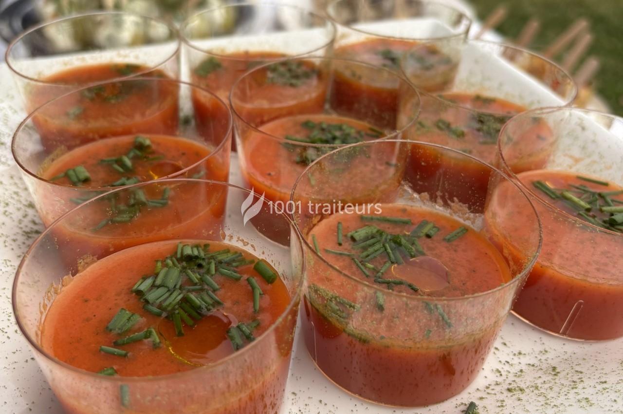 Verrines de soupe froide rouge garnies de ciboulette fraîche, présentées sur un plateau blanc.